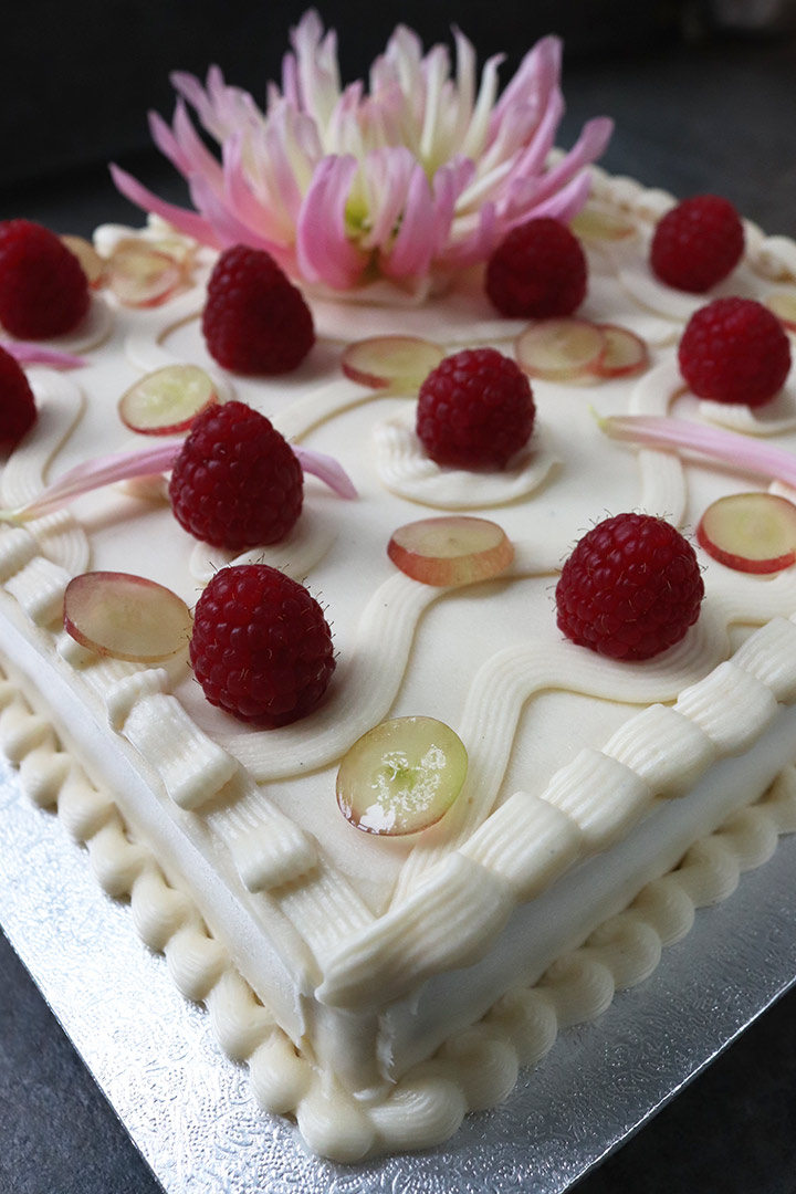 Glutenfree, dairyfree vegan October birthday cake: a vegan carrot cake, made with organic ingredients and frosted with vegan cream cheese buttercream. With piped buttercream, grapes, organic berries and dahlias